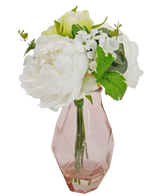 Le Bouquet Artificiel en Verre 25 cm présente un petit bouquet de fleurs blanches aux feuilles vertes, disposées dans un vase en verre rose clair facetté.