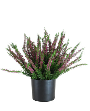 De Kunstplant Erica 33 cm is een rechtopstaande kunstplant in een zwarte pot, met bossige groene bladeren en talloze lange stelen versierd met kleine paarse en roze bloemen die zich naar buiten verspreiden.