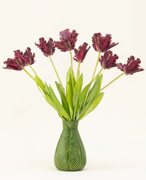 Le bouquet de fleurs artificielles en soie French Parakeet Tulip violet présente des tulipes violet foncé à franges avec de longues tiges vertes dans un vase avec un motif de feuilles vertes, créant un affichage saisissant sur un fond blanc.