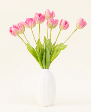 Le bouquet de fleurs artificielles en soie French Tulip rose est disposé dans un vase blanc, avec des tulipes françaises roses et des feuilles vertes sur un fond clair simple.