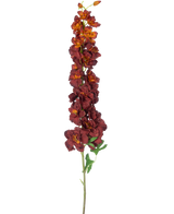La Fleur artificielle Delphinium 105 cm bordeaux a une longue tige unique avec plusieurs fleurs artificielles rouge foncé et orange et des feuilles vertes, isolées sur un fond blanc.