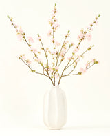 Le bouquet de fleurs artificielles en soie Fleur de cerisier rose clair 94 cm présente de délicates fleurs de cerisier artificielles roses dans un vase en céramique blanche, qui ajoute de l'élégance sur un fond clair et uni.