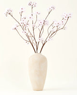 Le bouquet de fleurs artificielles en soie Fleur de cerisier rose clair 114 cm se dresse dans un grand vase en céramique beige avec de longues et fines branches et de délicates fleurs rose clair, créant un accent floral artificiel serein sur un fond uni.