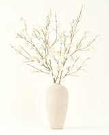 Het Zijden kunstbloemen boeket Eucalyptus crème in een hoge, lichtbeige keramische vaas met transparante witte bladeren zorgt voor een serene sfeer in elk kunstbloemen interieur tegen een lichte achtergrond.