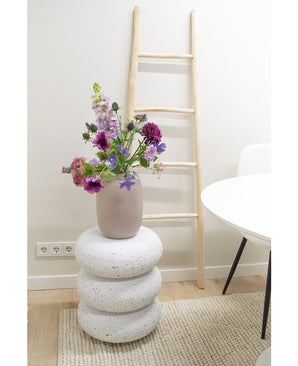 Une clochette de fleurs artificielles de 62 cm violette se tient dans un vase sur trois coussins ronds en forme de pierre blanche. Derrière, se trouve une échelle en bois clair contre un mur blanc, à côté d'une table et d'une chaise blanches sur un tapis beige.