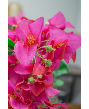 Un gros plan de la fleur artificielle Bougainvillier 90 cm violet montre des fleurs artificielles violettes vibrantes avec des bourgeons verts sur un arrière-plan légèrement flou.
