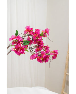 La fleur artificielle Bougainvillier 90 cm violet, avec des fleurs violettes vibrantes et des feuilles vertes, est présentée sur un fond neutre clair à côté d'une échelle en bois à droite.