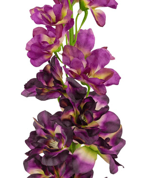 Gros plan de la fleur artificielle Delphinium Purple 79 cm, une haute tige artificielle avec de multiples fleurs violettes et violet foncé avec un cœur vert et jaune, sur fond blanc.