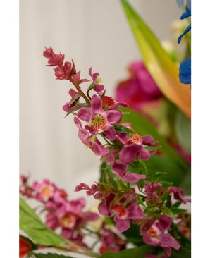 Gros plan de la fleur artificielle Cataire 75 cm rose : une grappe de fleurs artificielles rose vif avec un cœur vert et des feuilles luxuriantes, nettement représentées sur un fond légèrement flou avec des notes d'autres fleurs.