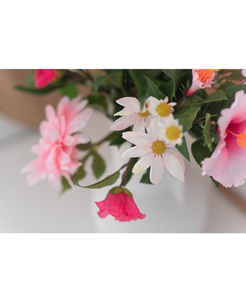 Een close-up van Kunstbloem Margriet 60 cm wit/roze toont roze en witte margrieten met een geel hart in een witte vaas tegen een neutrale achtergrond.