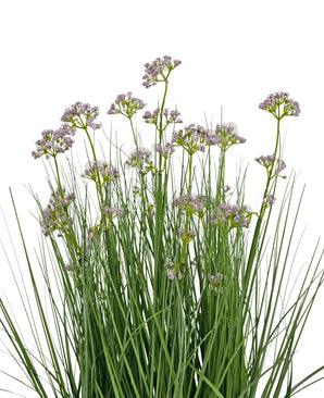 Le pot d'herbe d'oignon de fleur de poireau artificiel de 60 cm a des feuilles vertes hautes et fines et des bouquets de petites fleurs violettes claires délicates sur de longues tiges. L’arrangement est ignifuge et représenté sur un fond blanc.