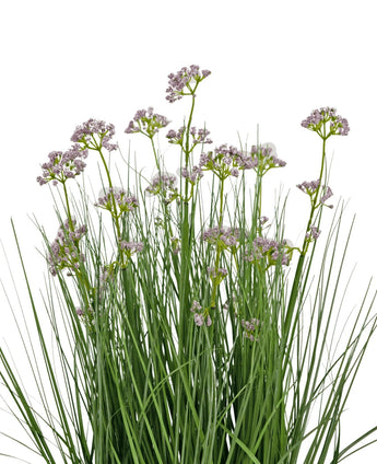 Le pot d'herbe d'oignon de fleur de poireau artificiel de 60 cm a des feuilles vertes hautes et fines et des bouquets de petites fleurs violettes claires délicates sur de longues tiges. L’arrangement est ignifuge et représenté sur un fond blanc.