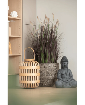 Une lanterne en bois, un grand pot en pierre avec un bonsaï d'oignon artificiel de 100 cm (ignifuge) et une statue de Bouddha grise sont disposés sur une surface de couleur claire, près d'une étagère en bois et d'un mur pâle.