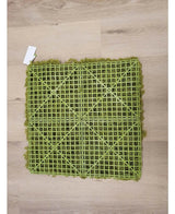 Le Artificial Haag Nordic Moss 50x50 cm UV est un tapis de gazon artificiel vert avec un dos en grille en plastique visible, idéal pour les intérieurs luxueux ou pour créer un mur végétal. Il repose sur un parquet en bois clair avec une petite étiquette blanche dans un coin.