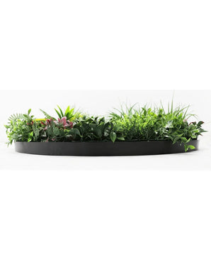 La Haie Artificielle sur Cadre Noir Ø100 cm est une jardinière noire semi-circulaire remplie d'un feuillage vert luxuriant et de quelques feuilles teintées de rose, sur un fond blanc.