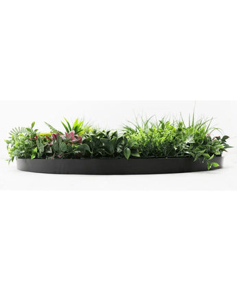 La Haie Artificielle sur Cadre Noir Ø100 cm est une jardinière noire semi-circulaire remplie d'un feuillage vert luxuriant et de quelques feuilles teintées de rose, sur un fond blanc.