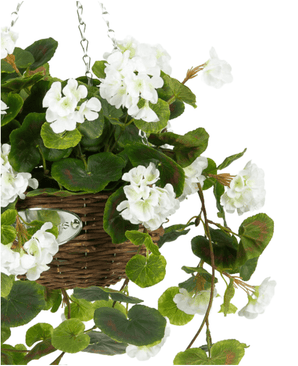 De Kunst begonia Wit in Mand UV 70cm heeft weelderige groene bladeren en witte bloemen in een hangende gevlochten mand, opgehangen aan een metalen ketting tegen een witte achtergrond.