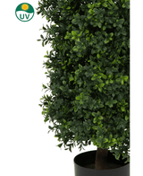Gros plan d'une plante artificielle pyramide de buis UV 90 cm aux feuilles vertes denses. Dans le coin supérieur gauche se trouve un symbole de protection UV avec un soleil jaune et « UV » dans un cercle vert.