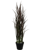Le gazon artificiel Bordeaux UV 90 cm est une grande plante artificielle aux feuilles longues et étroites, vert foncé et marron, dressées verticalement dans un pot noir, sur un fond blanc uni.