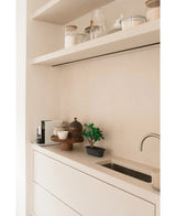 Comptoir minimaliste avec un petit évier, des pots décoratifs, une cafetière et des bacs sur étagères flottantes. Dans la palette de couleurs neutre blanc-beige, le bonsaï artificiel Ficus 30 cm est utilisé comme plante en pot d'accent.