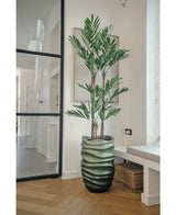 De Kunstplant Parlour Deluxe 120 cm heeft dunne stelen en lange groene bladeren in een golvende groene vaas, perfect voor lichte moderne kamers met lichte houten vloeren en grote ramen.