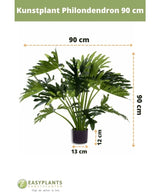 Plante artificielle Philodendron UV 90 cm en pot noir, avec des feuilles de 90 cm de large. Parfait pour n’importe quel espace. Taille du pot : 12 cm de haut, 13 cm de large. Logo Easyplants en bas.