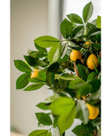 Un gros plan du citronnier artificiel de 75 cm, avec des feuilles vertes luxuriantes et des citrons jaunes vifs, placé à l'intérieur dans d'élégants pots décoratifs avec une douce lumière naturelle en arrière-plan.