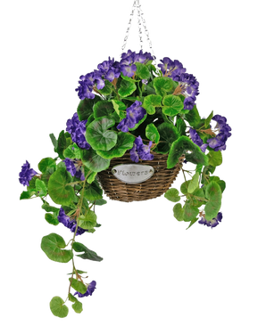 De Kunstbegonia paars in mand UV 70cm is een hangende rieten mand met groene bladeren en levendige paarse bloemen, opgehangen aan een zilveren ketting en voorzien van een klein metalen label met de tekst "Flowers.