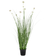 De Kunstgras Prei Bloem Uien Graspot 90cm brandvertragend heeft lange, dunne groene bladeren en bleke bloemtrossen in een zwarte pot, tegen een effen witte achtergrond.
